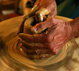 potters hands forming a centred piece of clay on the potters wheel